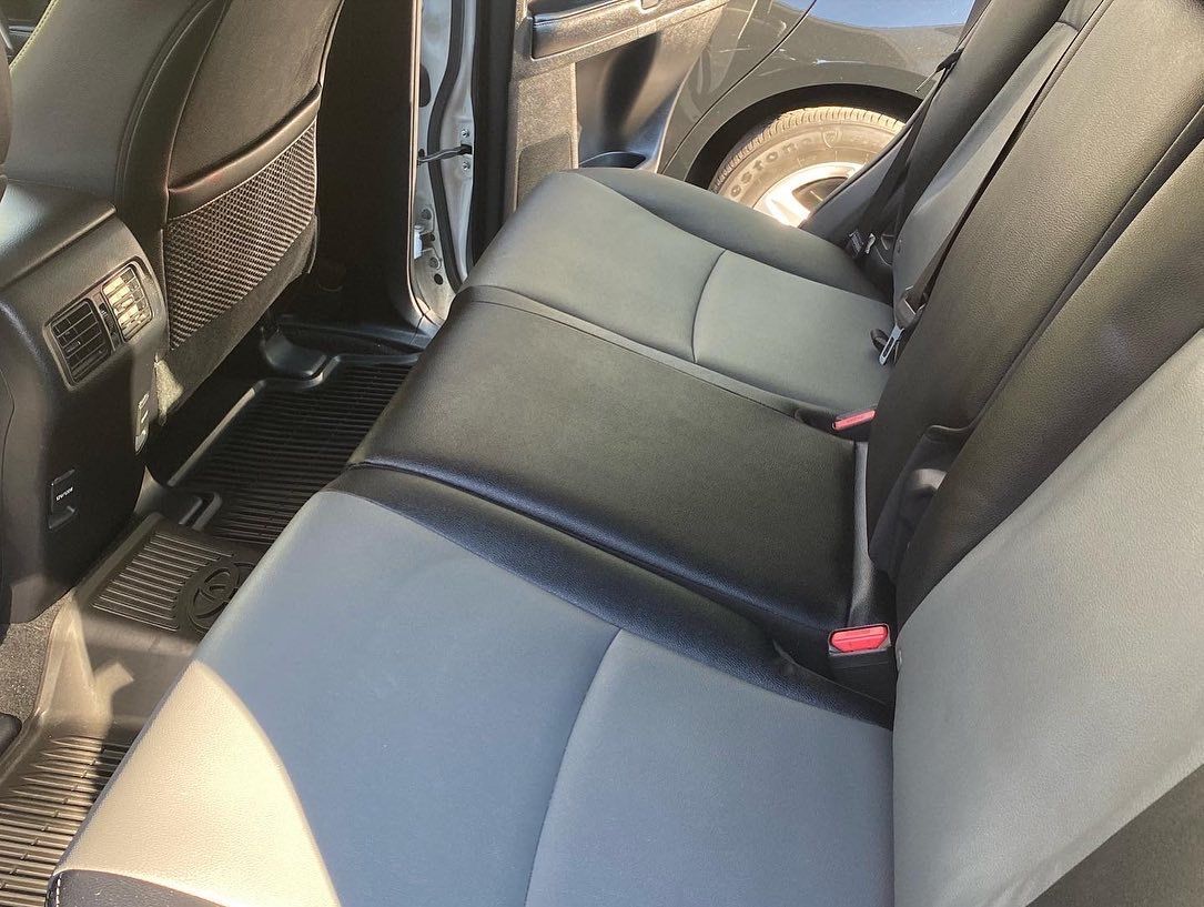 Gray and black car backseat with headrests, seatbelts, and a storage pocket.