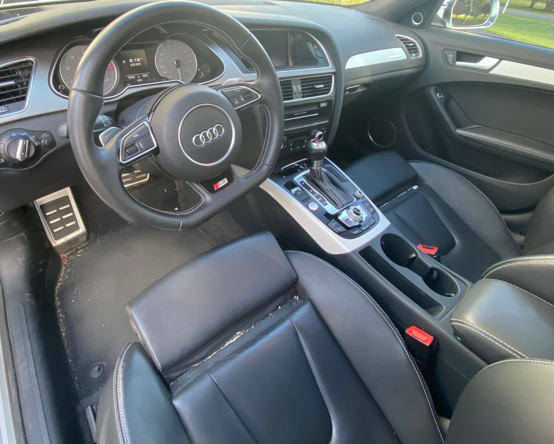 Black leather interior of an Audi S4, featuring a steering wheel, gear shift, and front seats.
