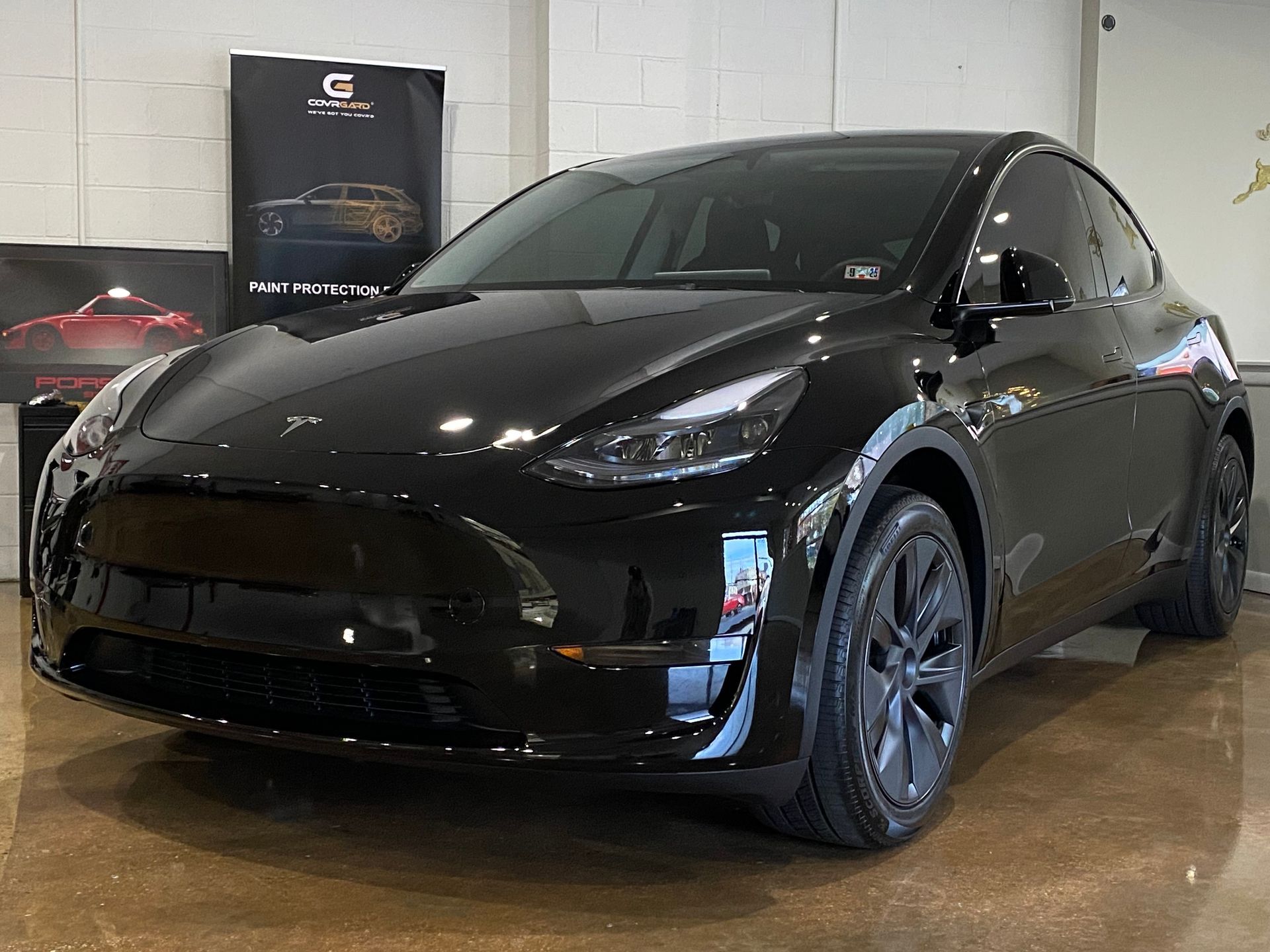 Black Tesla Model Y SUV parked inside, showroom setting.