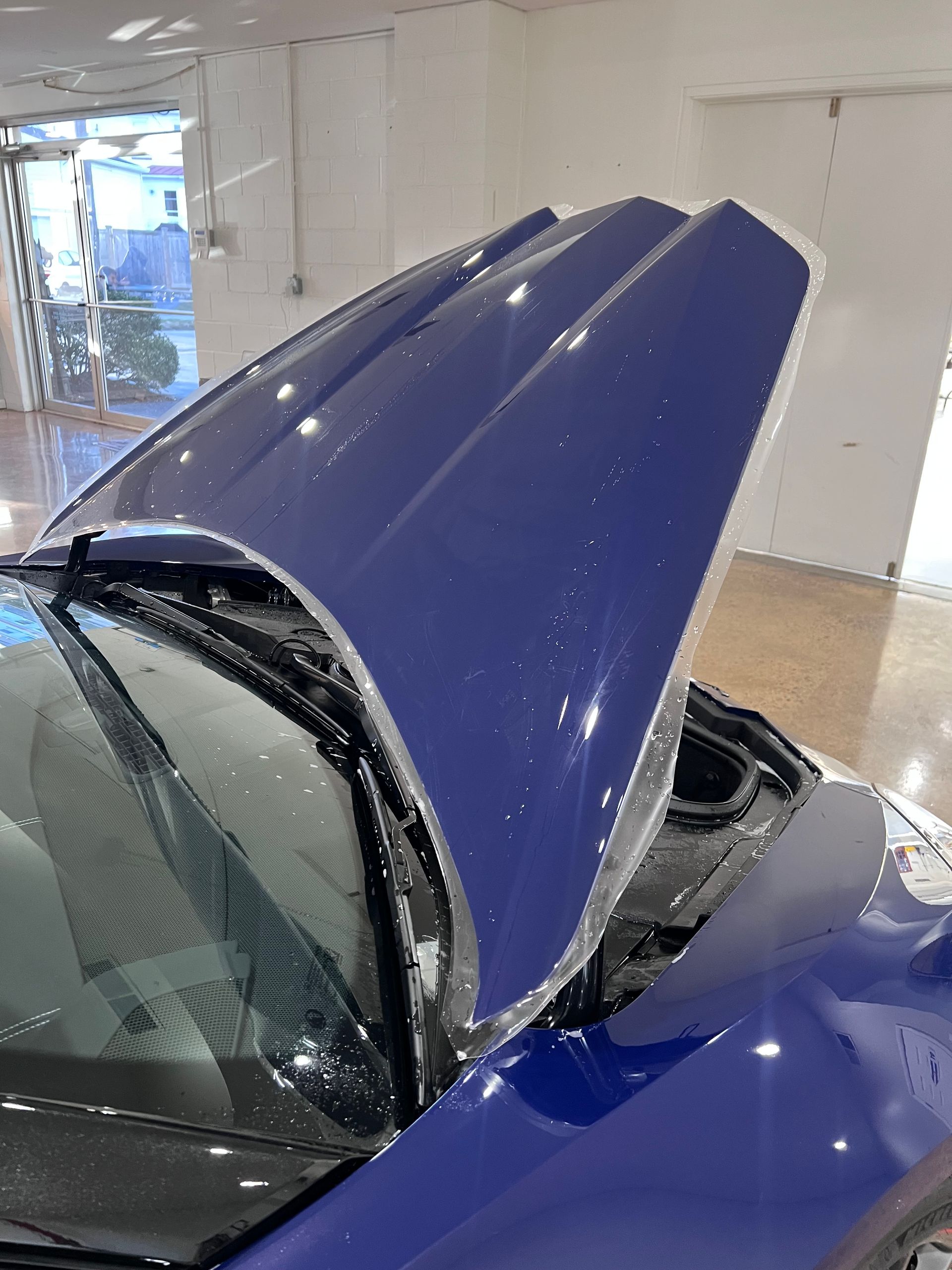 Black sports car with a damaged front bumper in a garage, viewed from the front-left side