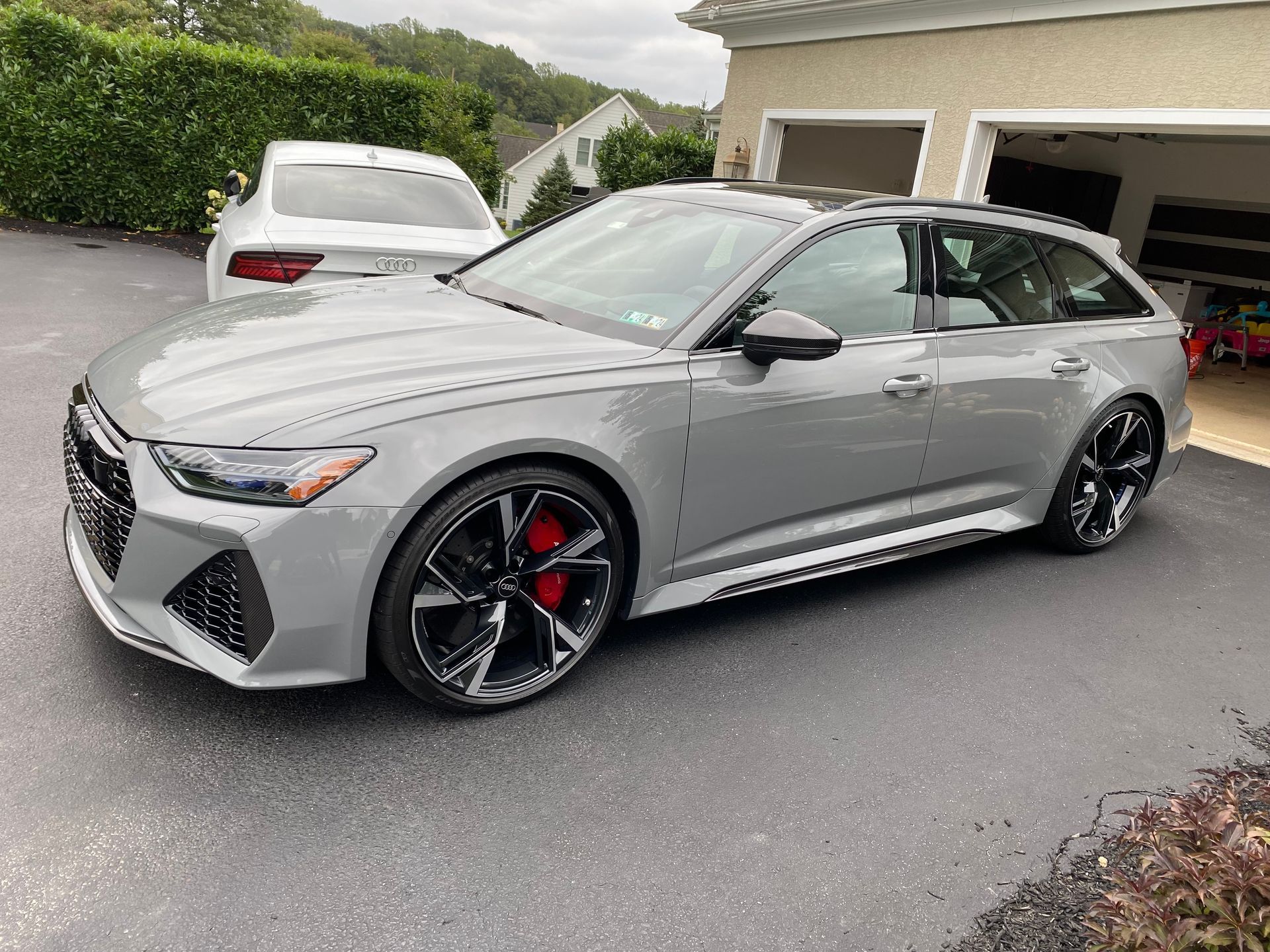 Silver sedan parked in a driveway beside a garage, with black wheels and red brake calipers