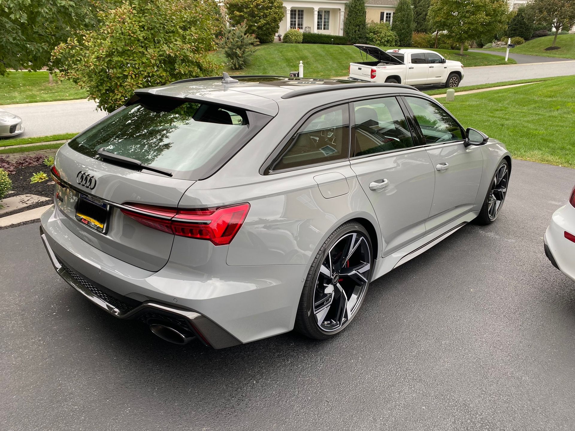 Silver Audi wagon parked on a suburban street with a roof box, viewed from the rear side.