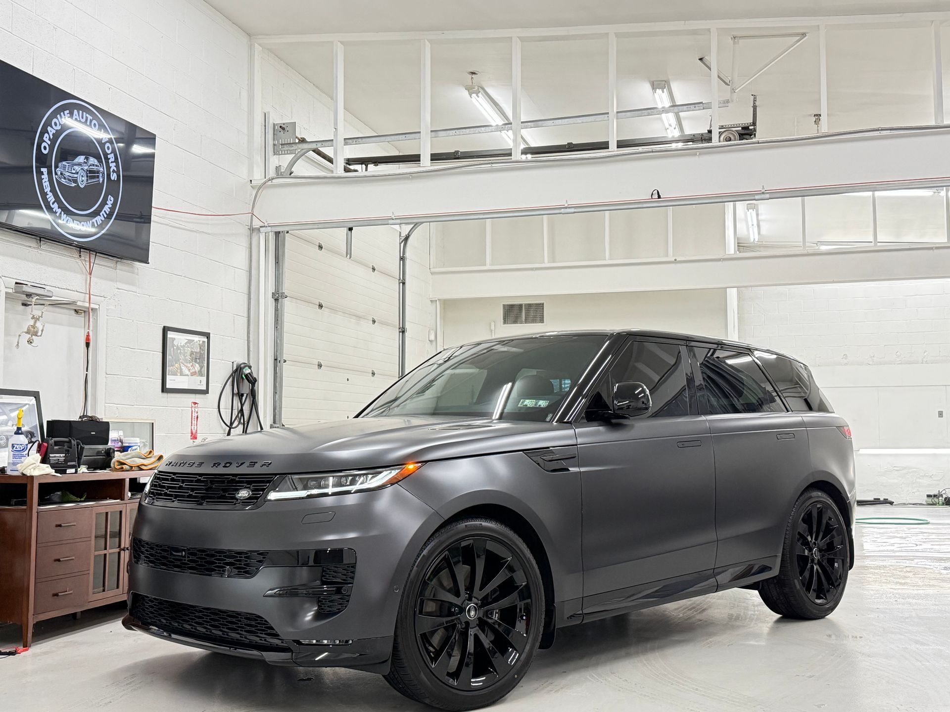Dark gray Range Rover Sport with black wheels inside a garage.