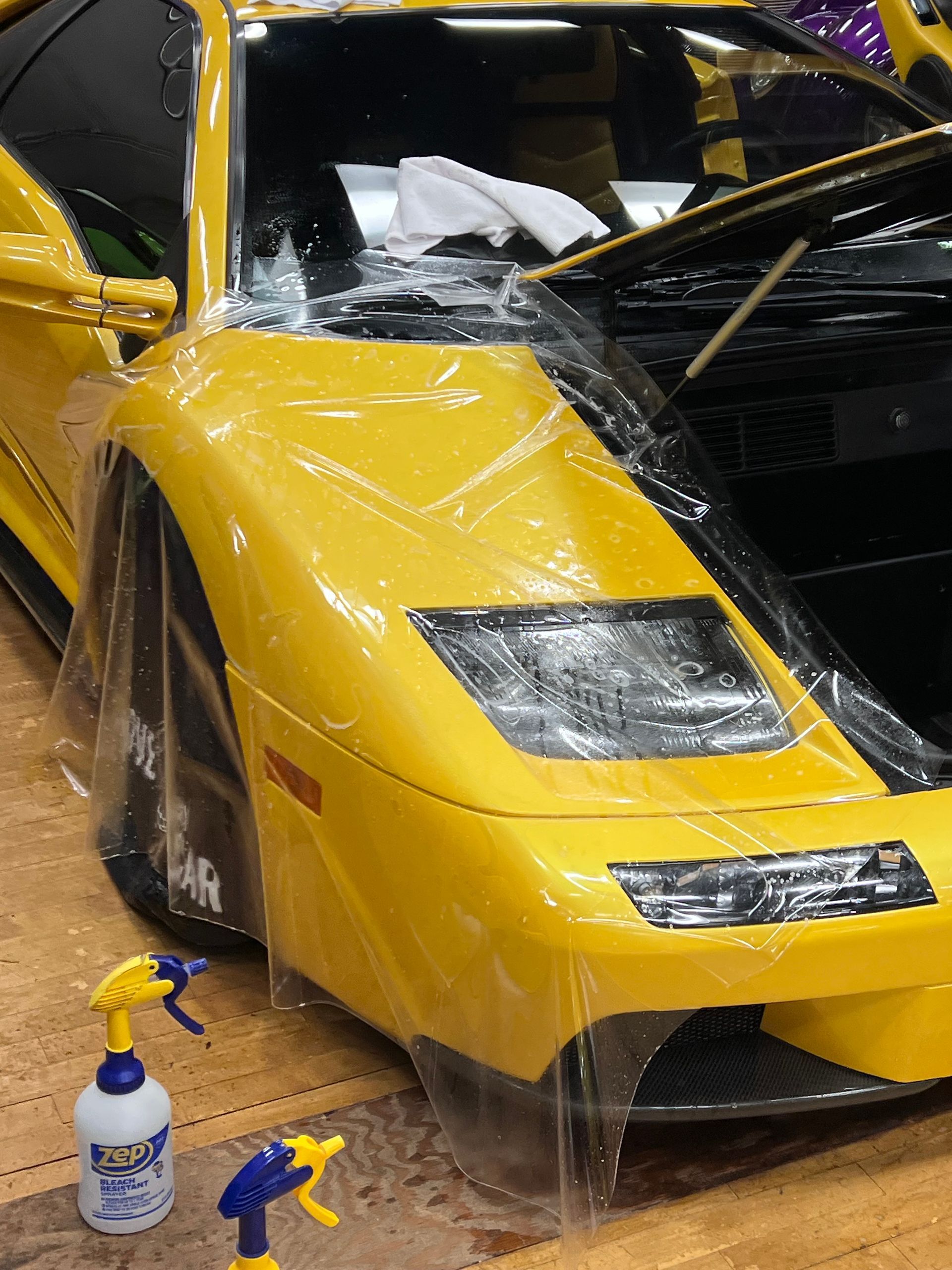 Black Porsche 911 in a showroom, front view with a carbon fiber hood and a spray bottle on the floor