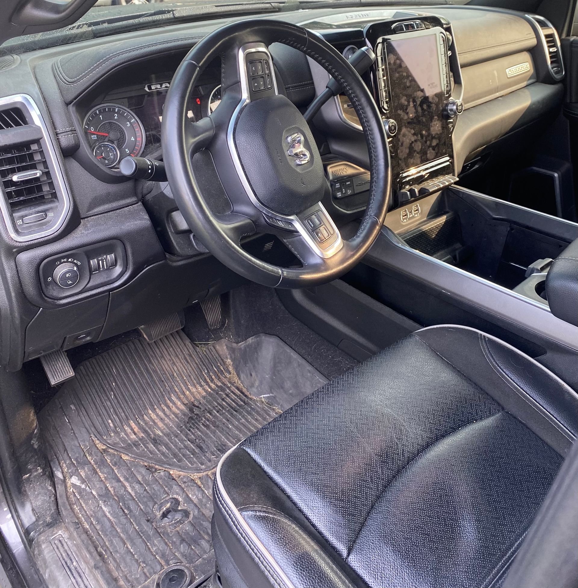 Interior view of a Ram truck, showing the dashboard, steering wheel, seats, and floor. Dark colors dominate the interior.