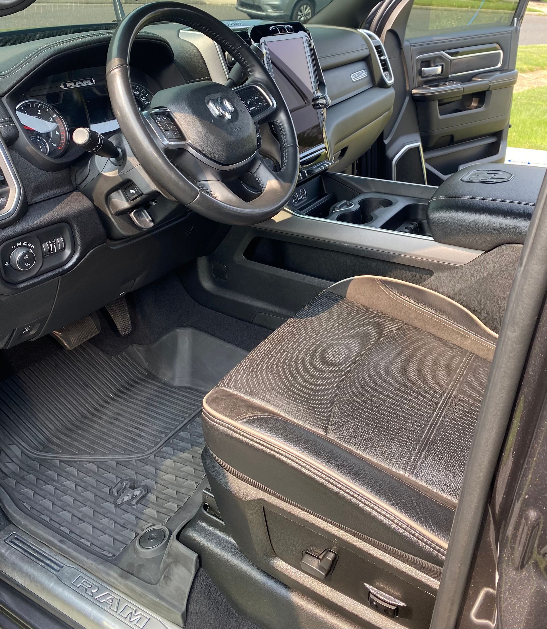Interior of a black Ram truck with a black steering wheel, seat, and floor mats.