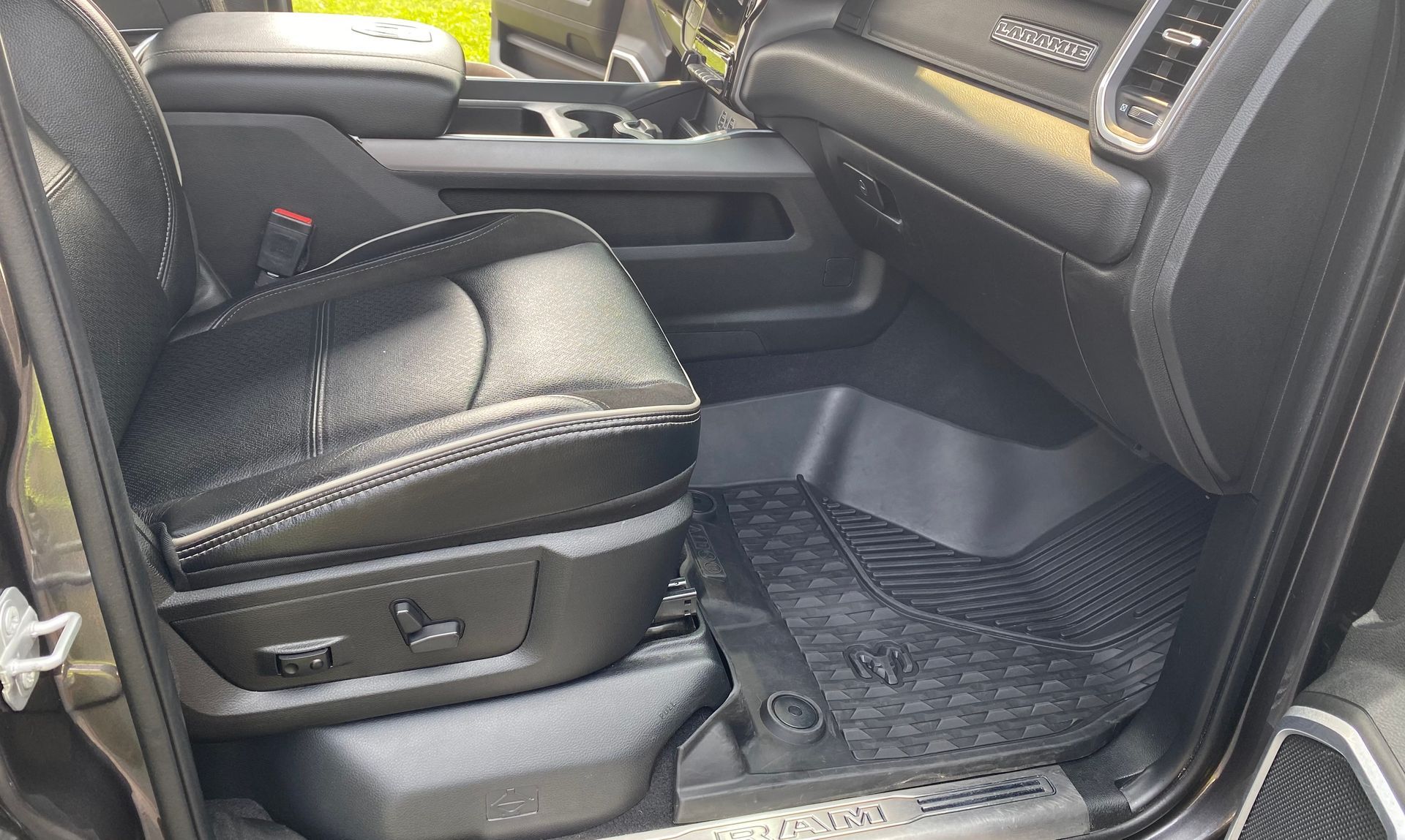 Black leather driver's seat in a Ram truck, with black rubber floor mat.