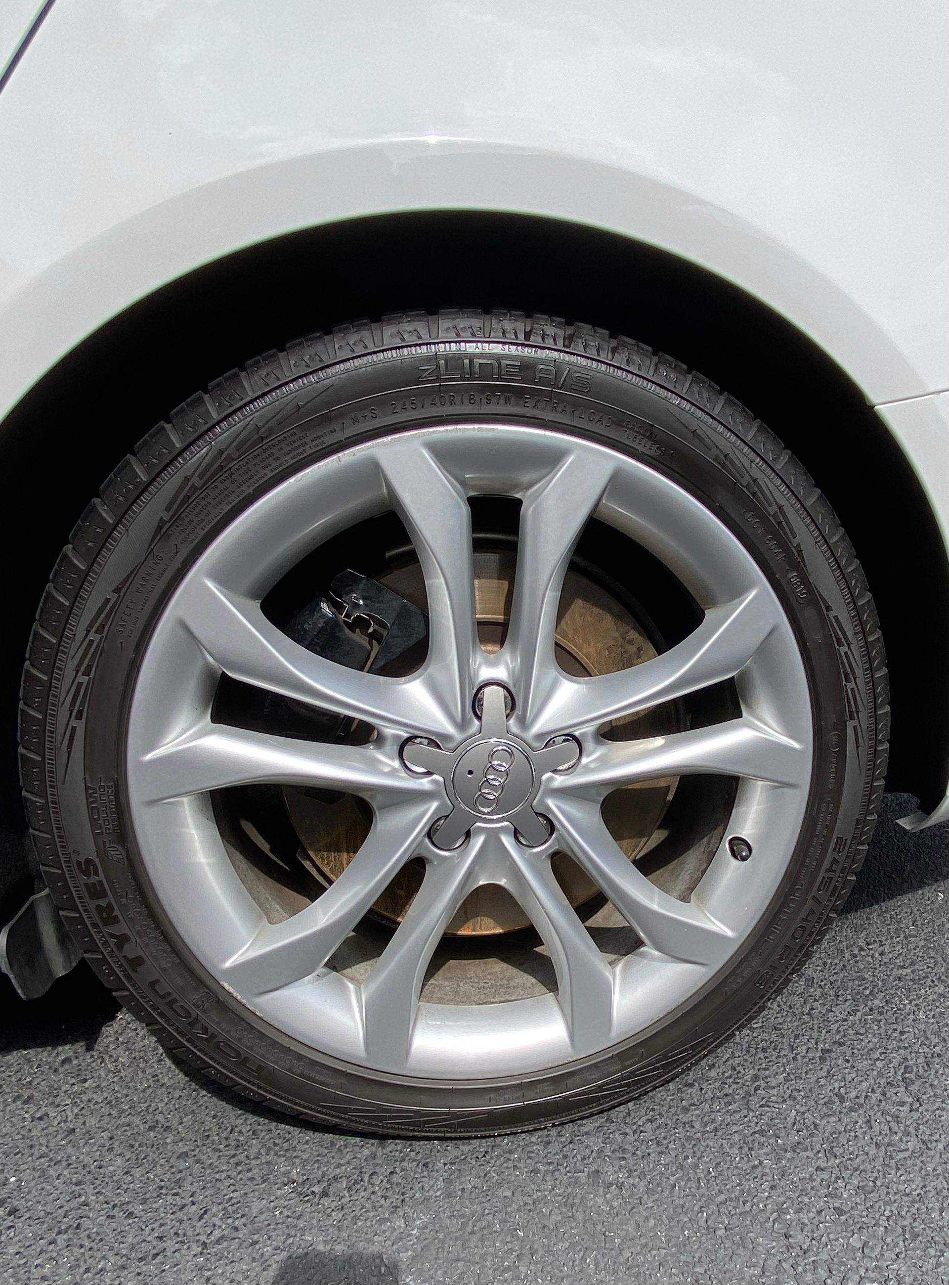 Silver car wheel with a black tire and an Audi logo.