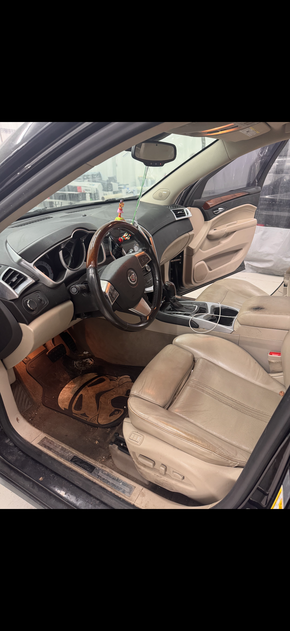 Interior view of a beige car. The steering wheel and seats are visible. Some dirt is on the floor.