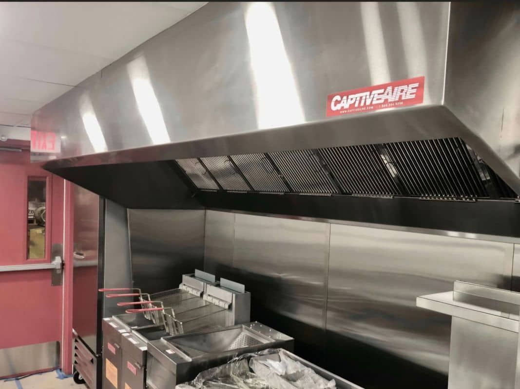 A kitchen with stainless steel appliances and a hood that says captive-aire
