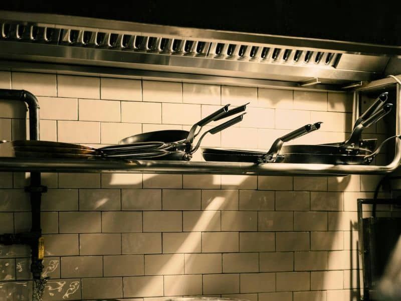 A bunch of pots and pans on a shelf in a kitchen