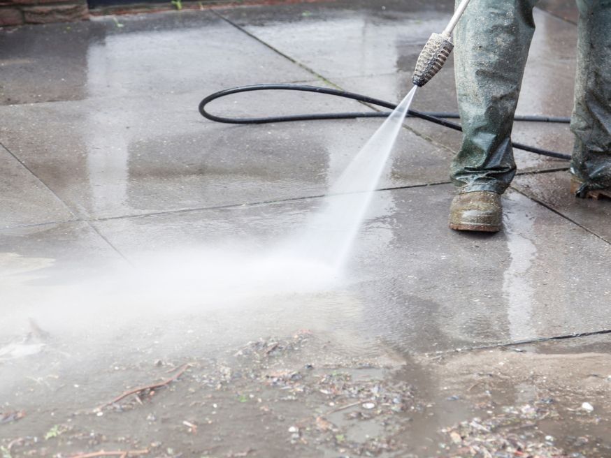 Parking Lot Power Washing A man is using a high pressure washer to clean a concrete floor.