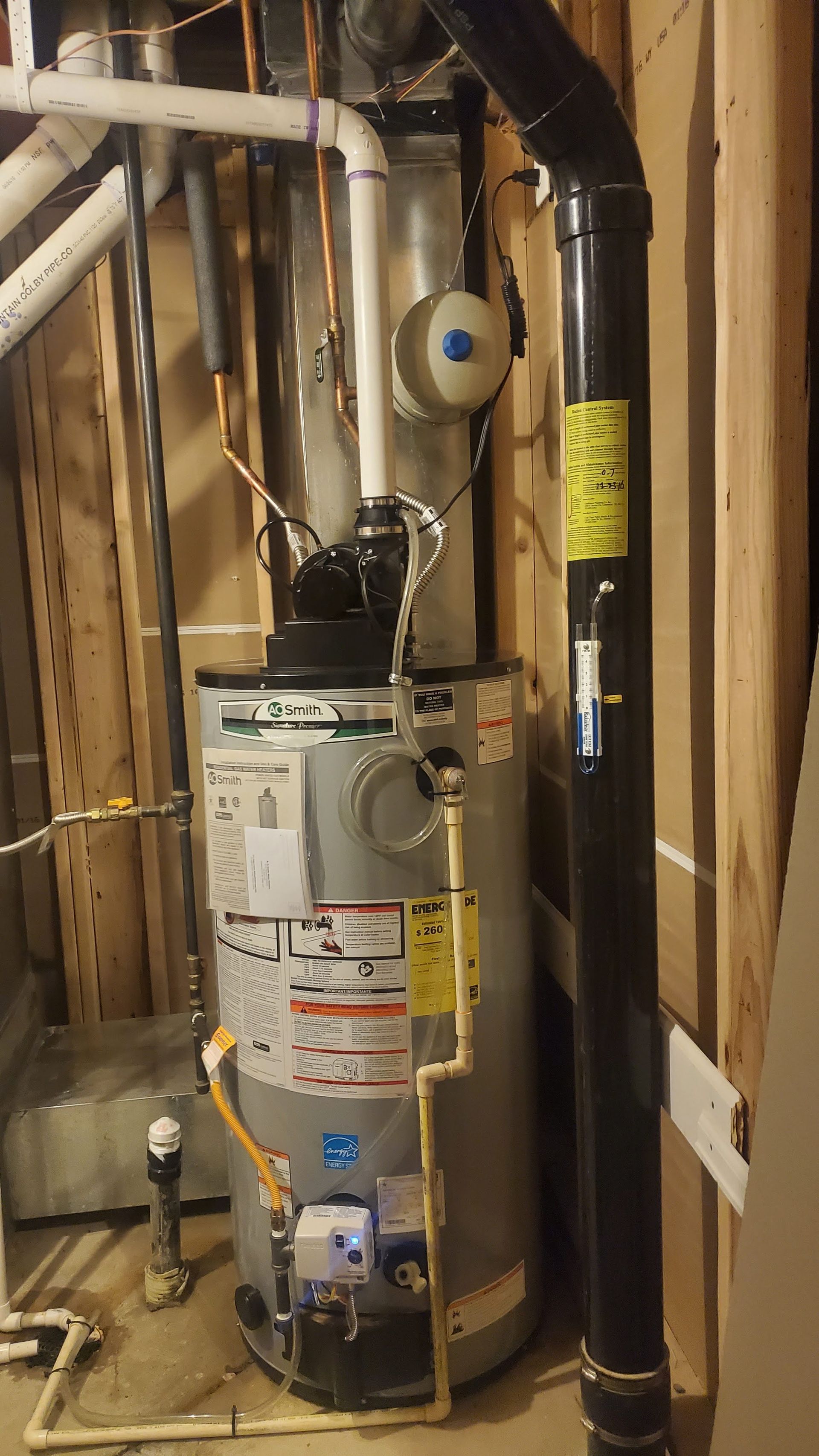 Water heater with connected pipes and vent in a utility room.