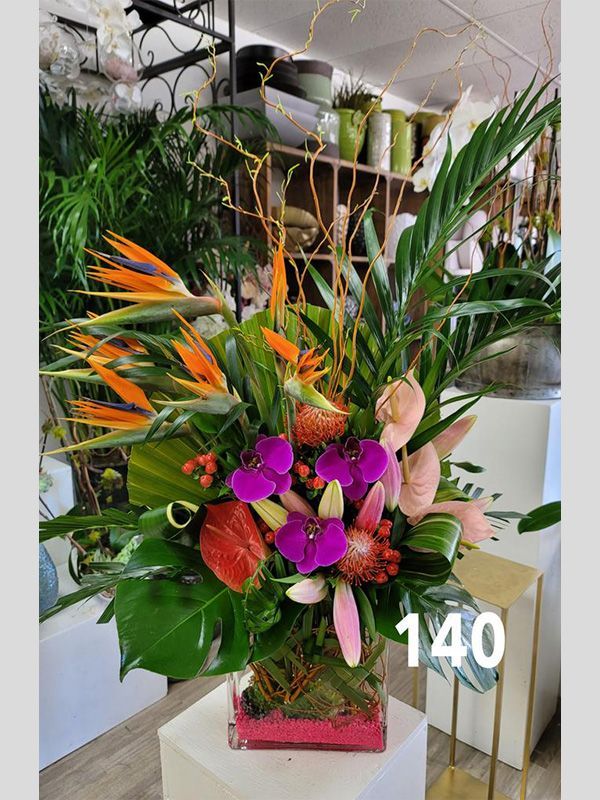 A vase filled with flowers and plants is sitting on a table.