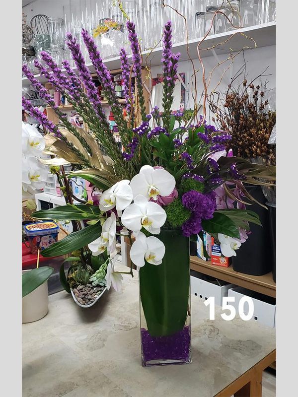 A vase filled with purple and white flowers is sitting on a table.