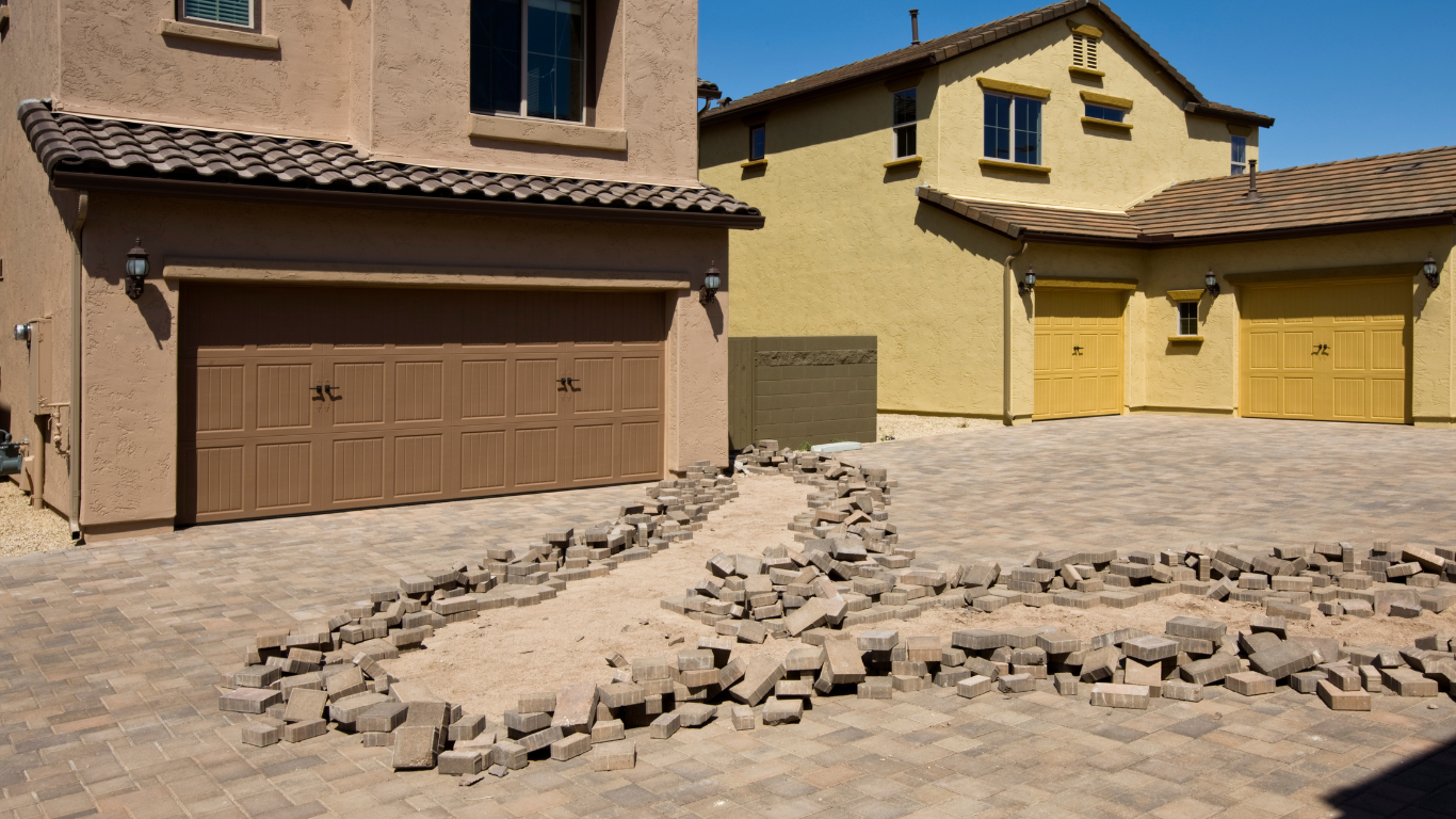 Two houses with brick driveways and a rock-lined path.