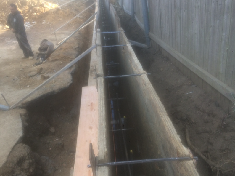 Construction of a concrete trench with rebar reinforcement; person in background.