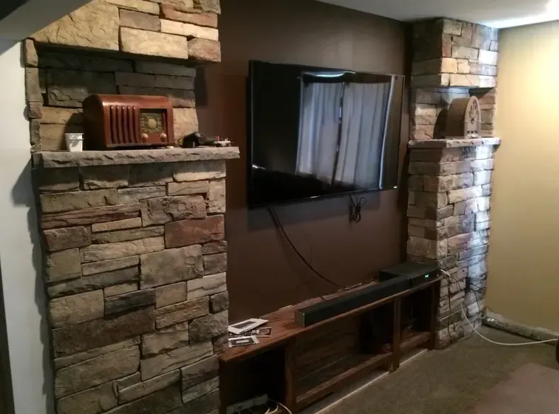 Stone fireplace with built-in shelves and a mounted TV. A radio and decor sit on the shelves.
