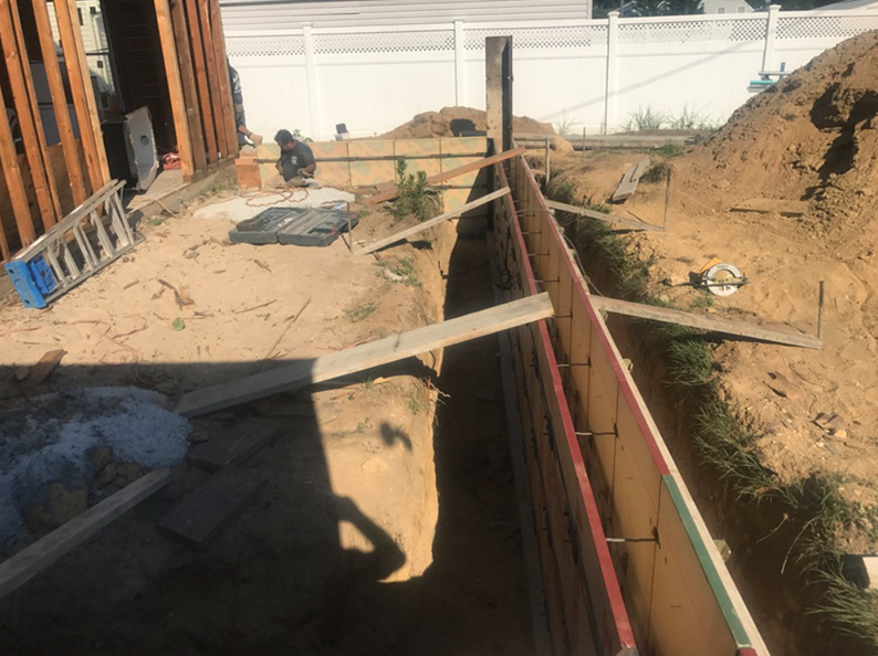 Construction site with wooden forms for concrete. A person works in the distance. Sunny day.