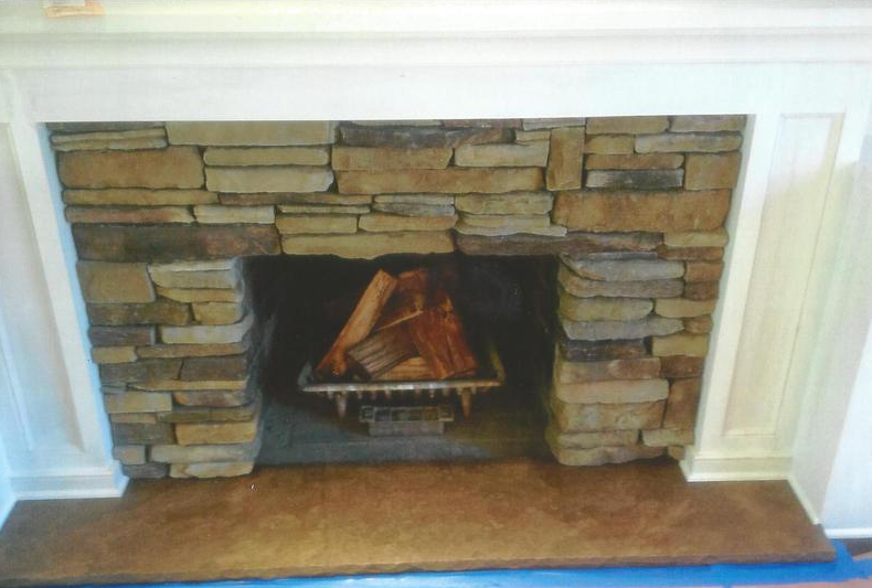 Stone fireplace with burning logs inside.