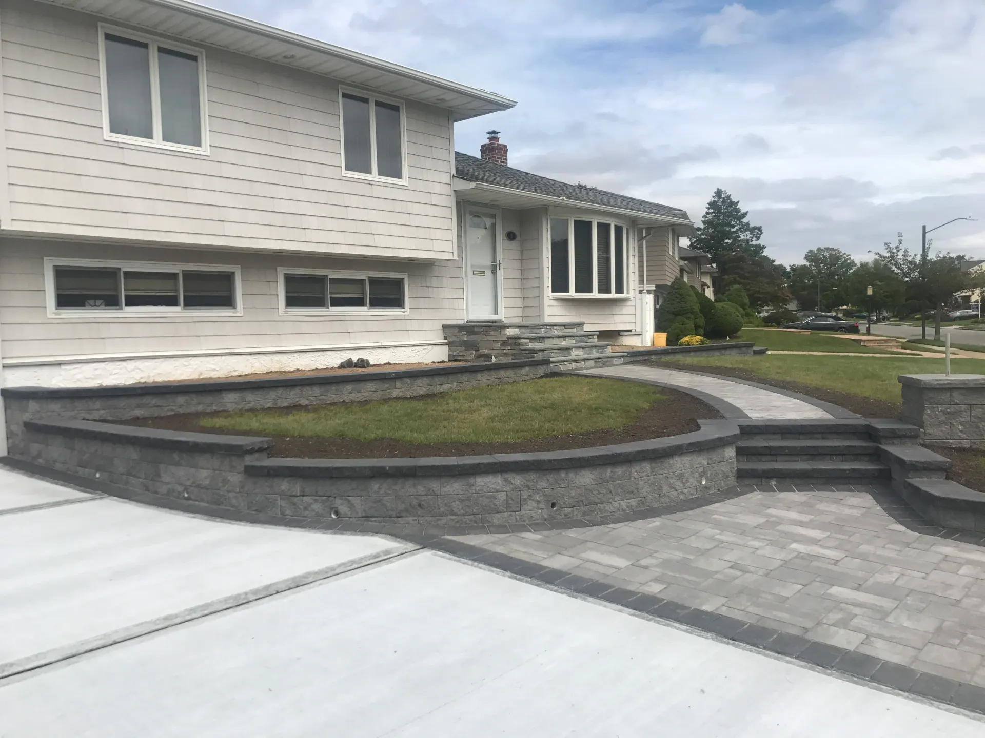 Gray house with a curved retaining wall, walkway and steps.