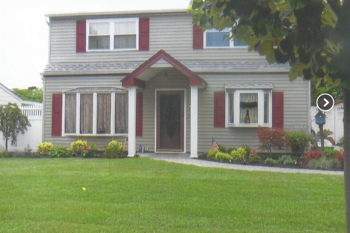 Two-story gray house with red shutters and a green lawn.