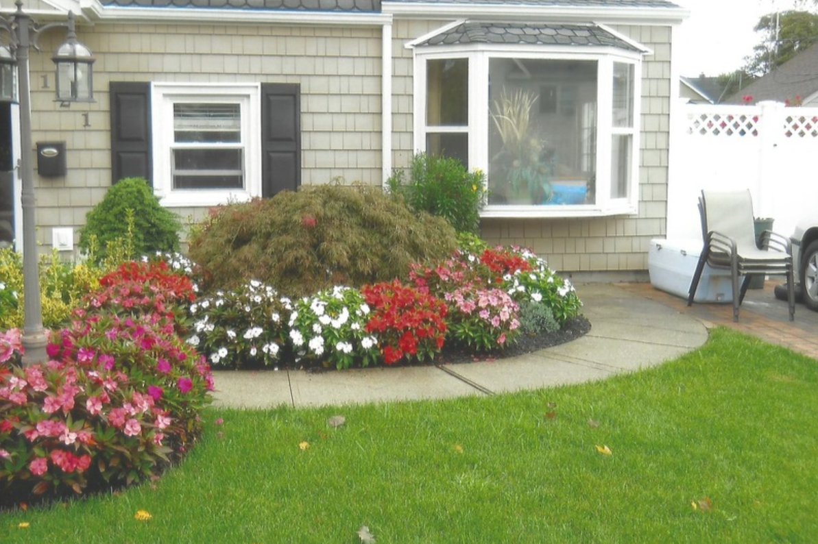 House exterior with colorful flowerbeds and a curved walkway.