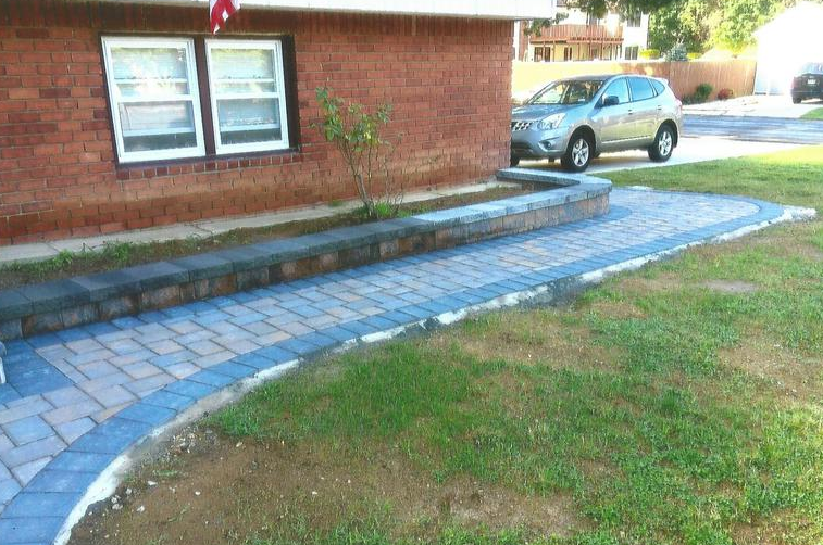 Brick home with brick walkway and retaining wall; SUV parked in driveway.