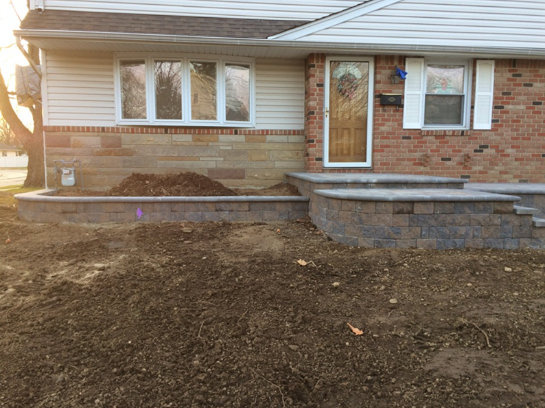 House exterior with new retaining wall, steps, and fresh soil.