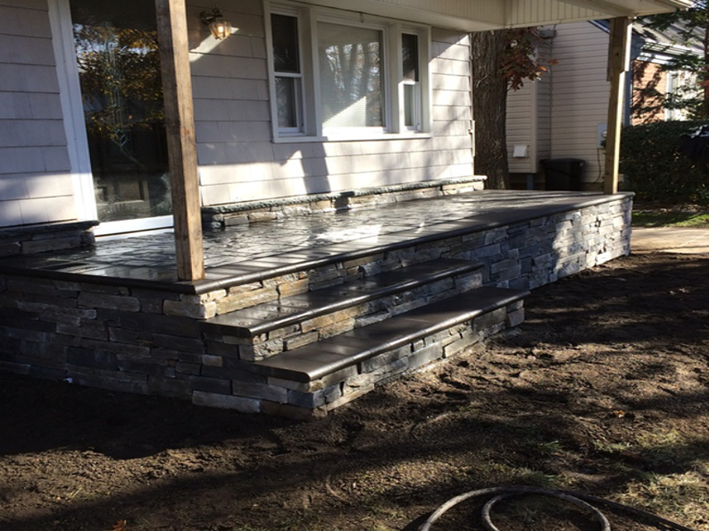 Stone porch with steps leading to a house with gray siding.