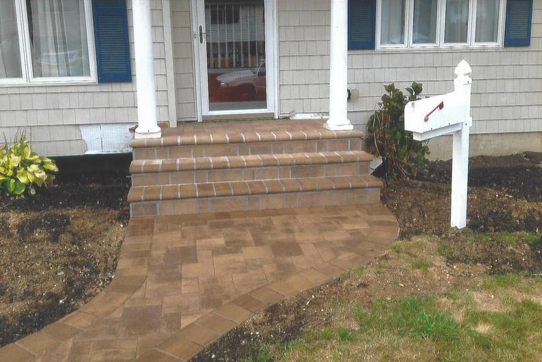 Brick steps and walkway leading to a house entrance with a mailbox on the right.