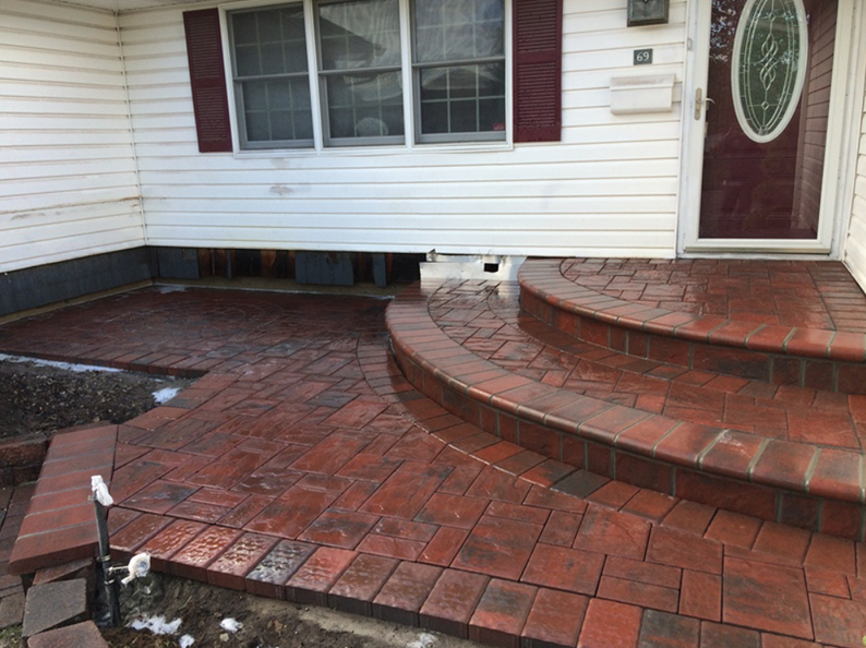 Red brickwork porch and steps leading to a white house's front door and window.