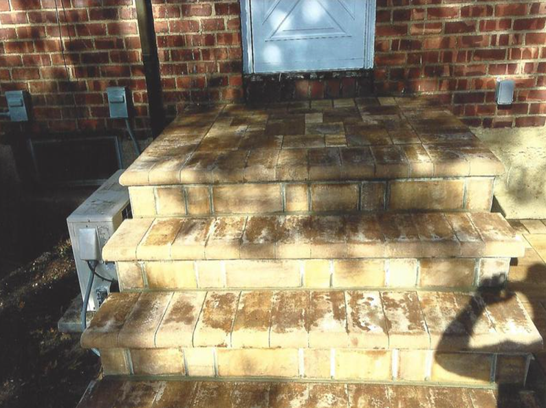 Brick steps leading up to a white door on a brick building.