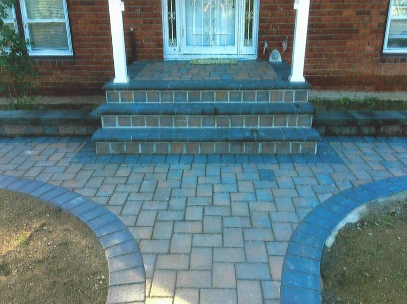 Brick walkway leading to a brick house entrance with steps and rounded borders.