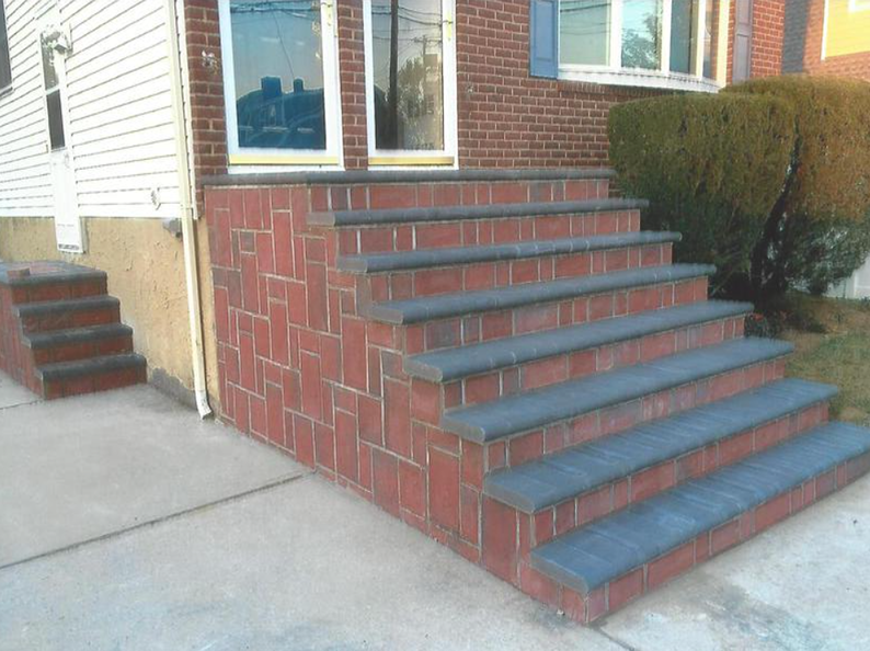 Brick steps leading to a house with dark gray caps and brick walls. Another smaller set of steps to the left.