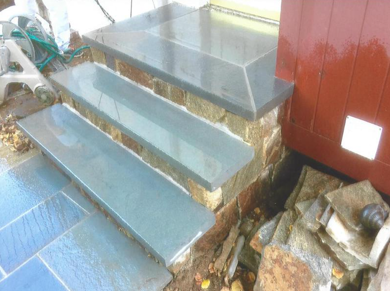 Stone steps leading up to a red door; blue-gray stone treads and tan stone risers.