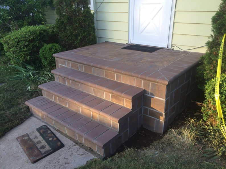 Brick steps leading up to a white door, with a small landing and welcome mat.