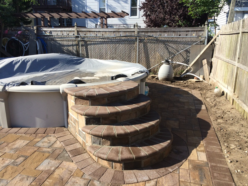 Brick steps leading to a covered above-ground pool, in a backyard setting.