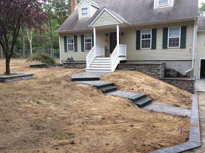 House with steps leading to the front door; a path and landscaping are under construction.