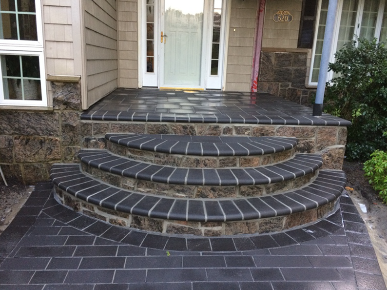 Brick steps leading up to a house's front door, with dark bricks and stone accents.