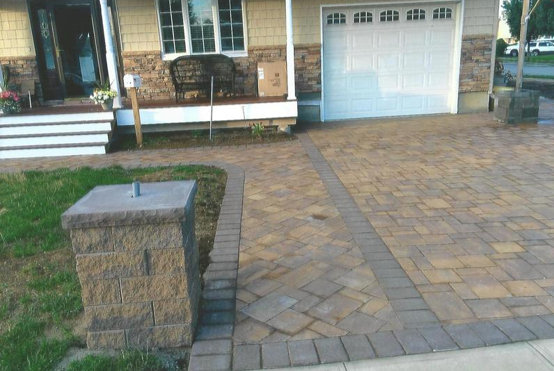 Brick driveway, walkway, and pillar in front of a house with a white garage door.