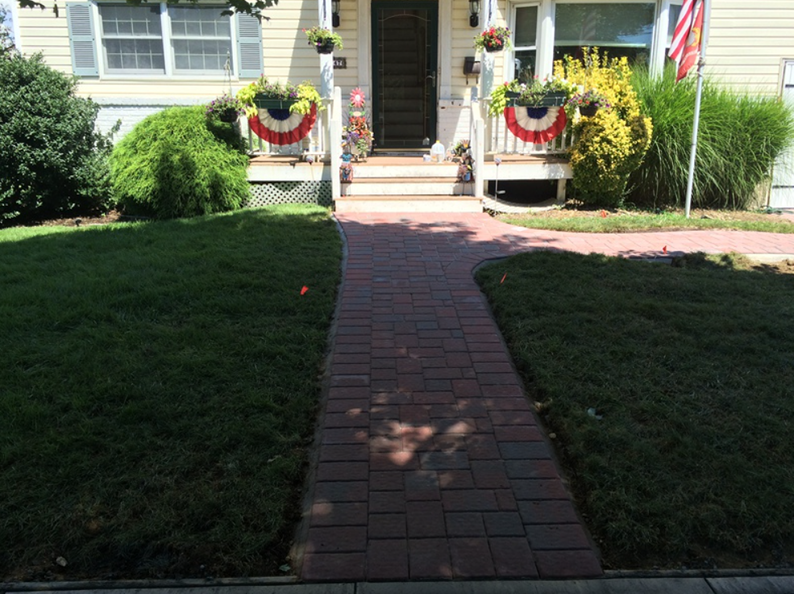 Brick path leading to a house with a decorated porch and well-kept lawn.