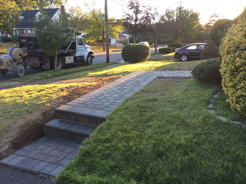 Brick pathway with steps and truck, on a residential street.