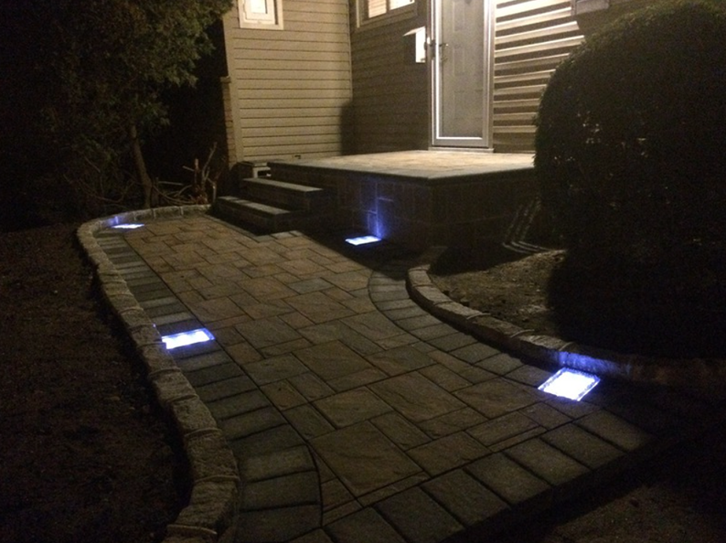 Dark path lit by blue lights, leading to a house entrance with steps.