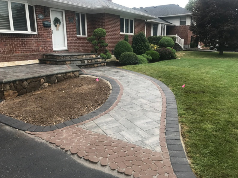 Brick home with paved walkway, landscaping, and steps leading to the front door.