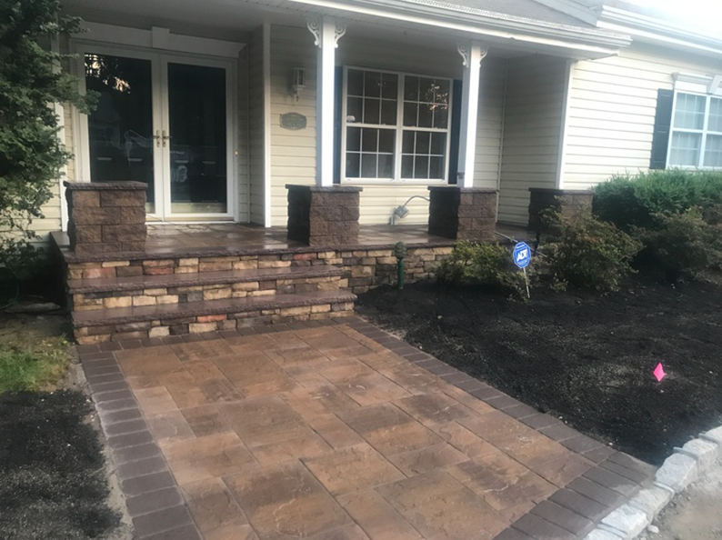 Brickwork pathway and steps leading to a house with columns and a window.