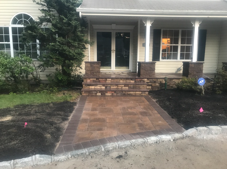 Paver walkway and steps leading to a house with stone facade accents.