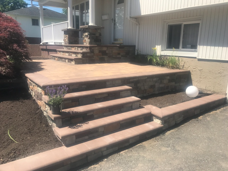 Stone steps and retaining walls leading to a home's front porch, surrounded by landscaping.
