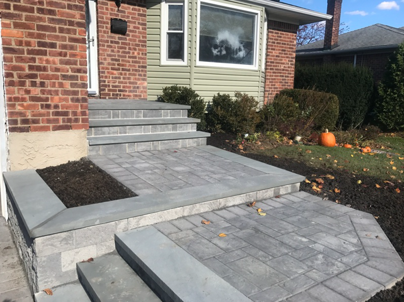 Brick house entrance with grey brick steps and patio.