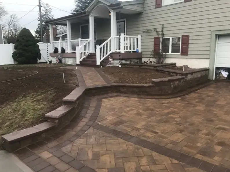 Brick pathway and steps leading to a house with a porch, flanked by low retaining walls.